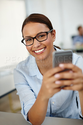 Buy stock photo Portrait of a young woman sitting with her cellphone at work