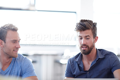 Buy stock photo Shot of two male colleagues discussing work in the office