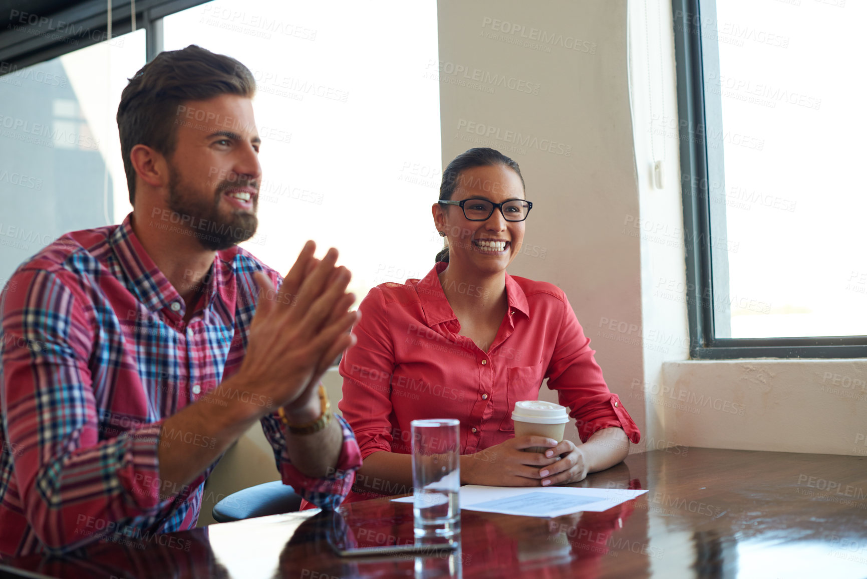 Buy stock photo Cropped shot of two young coworkers addressing someone out of shot