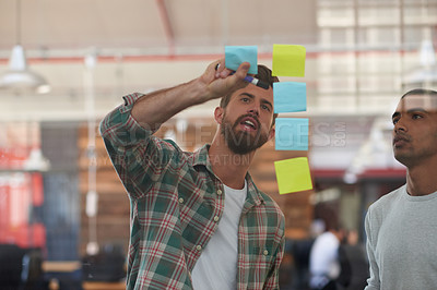 Buy stock photo Shot of two colleagues discussing ideas together on sticky notes