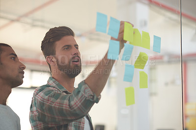 Buy stock photo Shot of two colleagues discussing ideas together on sticky notes