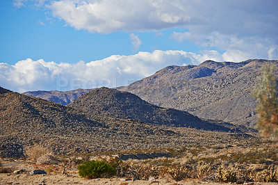 Buy stock photo Desert, landscape and nature with mountain, sunshine and clouds with summer, weather and rocky. Empty, flowers and wildlife with dust, field and plants with cactus, tourism and travel with adventure