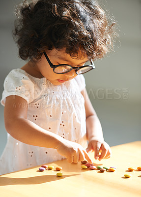 Buy stock photo Toddler, counting and sweets for learning math, equation or childhood development knowledge. Girl, glasses and candy  on table for intelligence growth or education homework, preschool or study reward