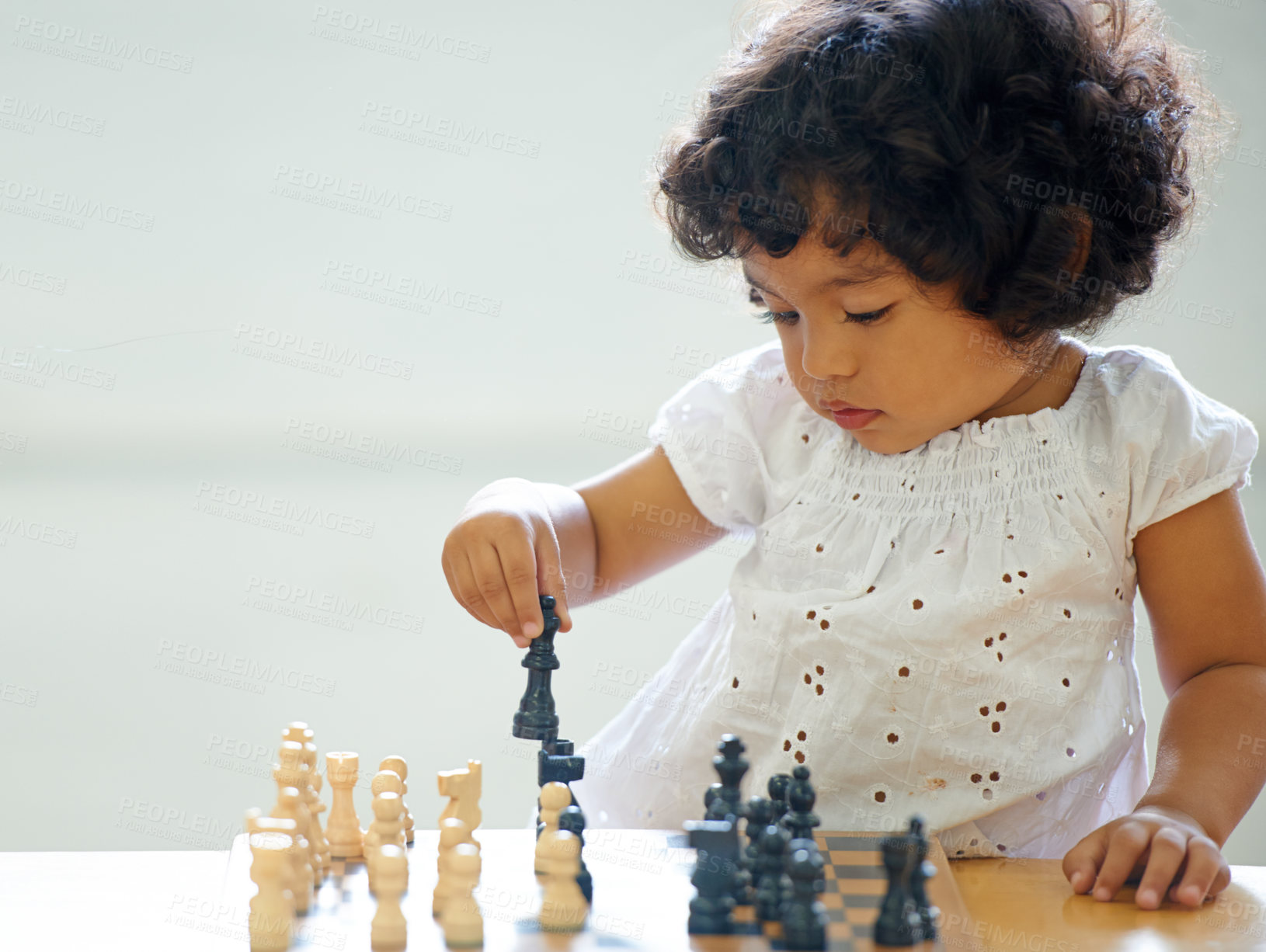 Buy stock photo Toddler, girl and chess play for learning growth, childhood development or thinking challenge. Female person, board game or table problem solving intelligence or kids, planning knowledge or education