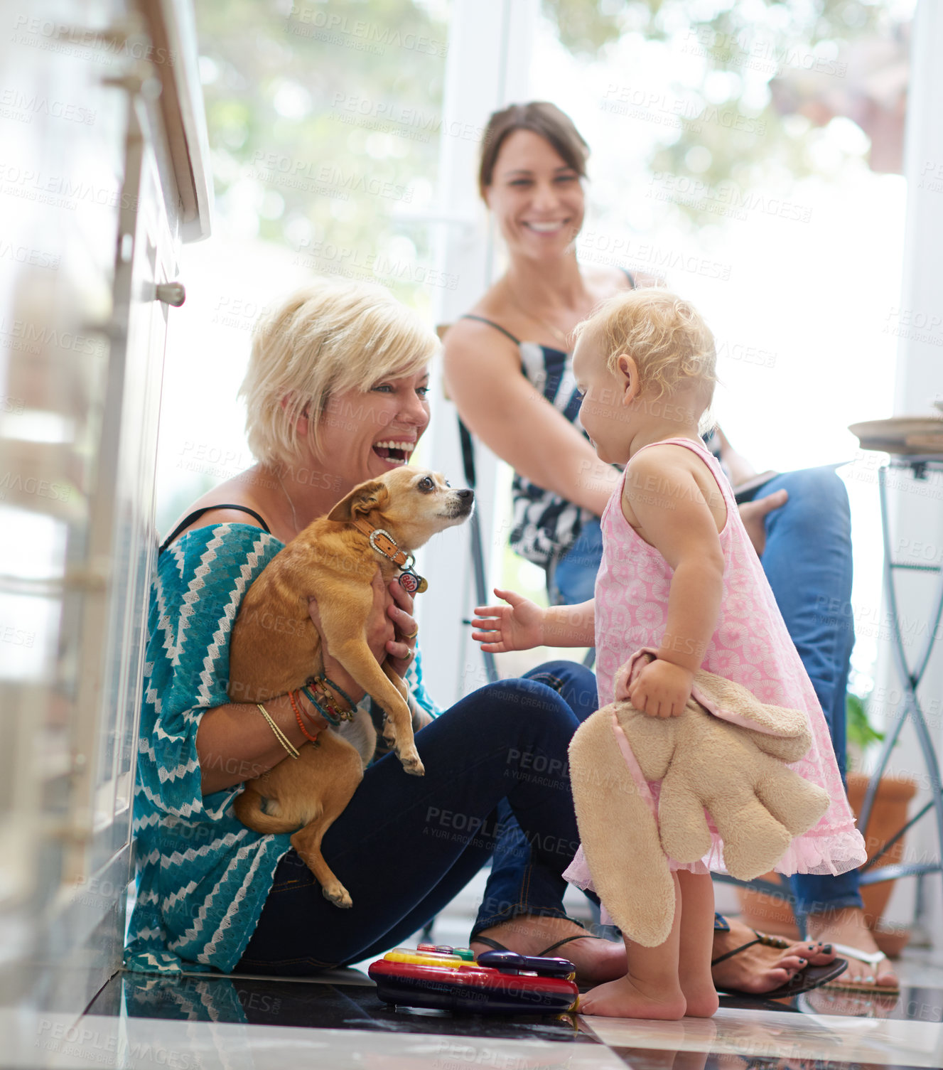 Buy stock photo Shot of a lesbian couple at home with their daughter and puppy 