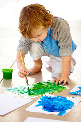 Buy stock photo Art, creative and a messy boy painting paper on the floor of his bedroom at home for school homework. Learning, growth and development with a young child using a paintbrush for artistic creativity