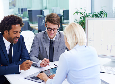 Buy stock photo Shot of three colleagues in an office looking at a digital tablet