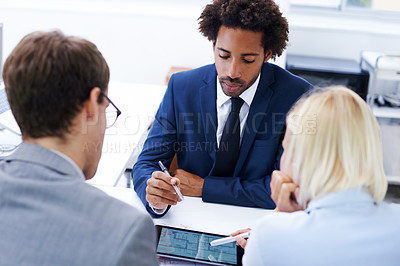 Buy stock photo Shot of a businessman looking at plans on a digital tablet with two colleagues