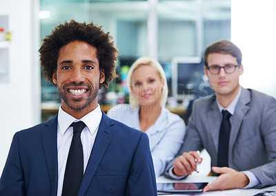 Buy stock photo Portrait of a businessman smiling at the camera with his colleagues in the background
