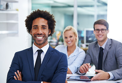 Buy stock photo Shot of a confident businessman smiling at the camera with colleagues in the background