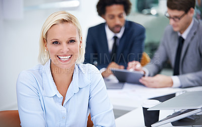 Buy stock photo Portrait of a confident businesswoman sitting at her desk with staff in the background