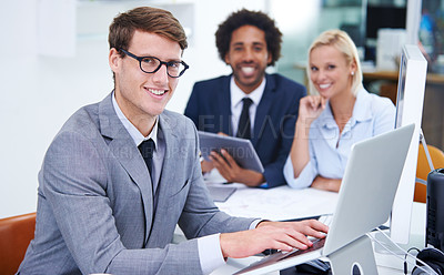 Buy stock photo Portrait of a confident businessman sitting in the office with his colleagues in the background