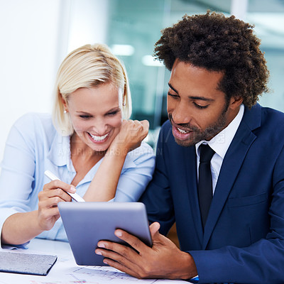 Buy stock photo Shot of two smiling colleagues working together on a digital tablet