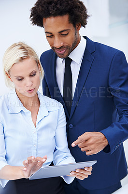 Buy stock photo Shot of two colleagues discussing information on a digital tablet