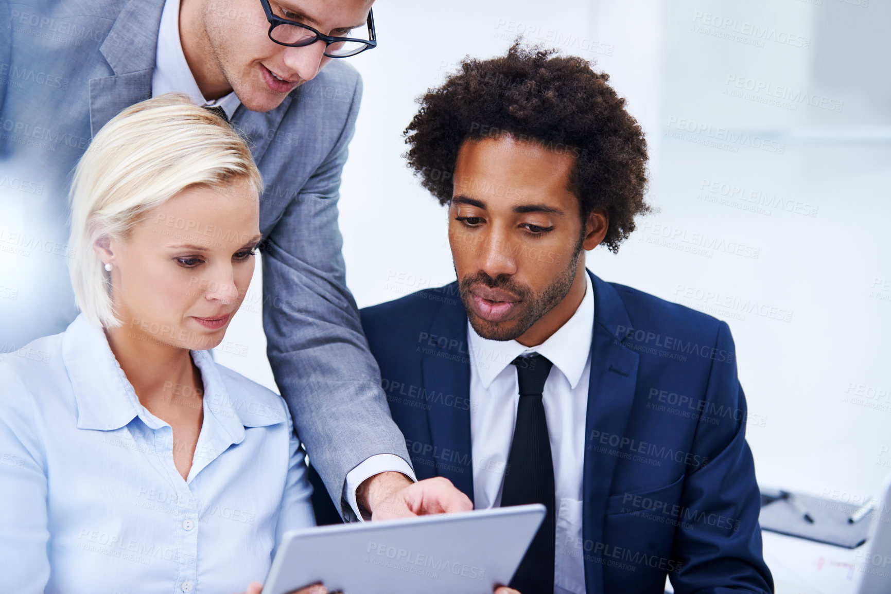 Buy stock photo Shot of a businessman pointing at something on a digital tablet to his colleagues