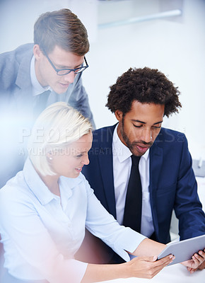 Buy stock photo Shot of three businesspeople looking at a digital tablet together
