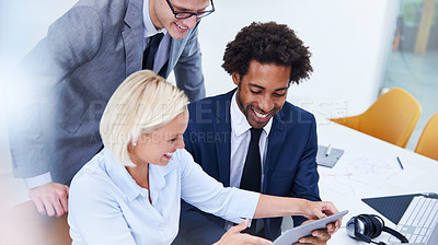 Buy stock photo Cropped shot of smiling colleagues looking at a digital tablet together