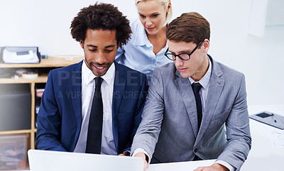 Buy stock photo Shot of three colleagues looking at a laptop together