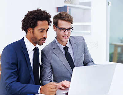 Buy stock photo Shot of two male colleagues working together on a laptop