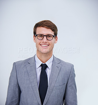 Buy stock photo Portrait of a young businessman smiling at the camera in front of a white background
