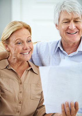 Buy stock photo Shot of a happy elderly couple going over their paperwork together at home