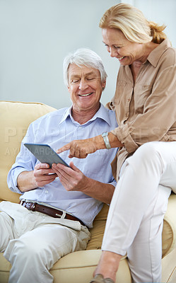 Buy stock photo Shot of a happy elderly couple using a digital tablet together at home