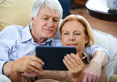 Buy stock photo Home, old couple and relax on sofa, tablet and connection with digital app, comfort and cozy. Apartment, senior woman and mature man on couch, tech and online reading for news, love and retirement