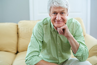 Buy stock photo Portrait of a senior man enjoying a comfortable retirement. A happy elderly guy sitting on the sofa at home. Mature retired male relaxing in the lounge and feeling positive at home. 