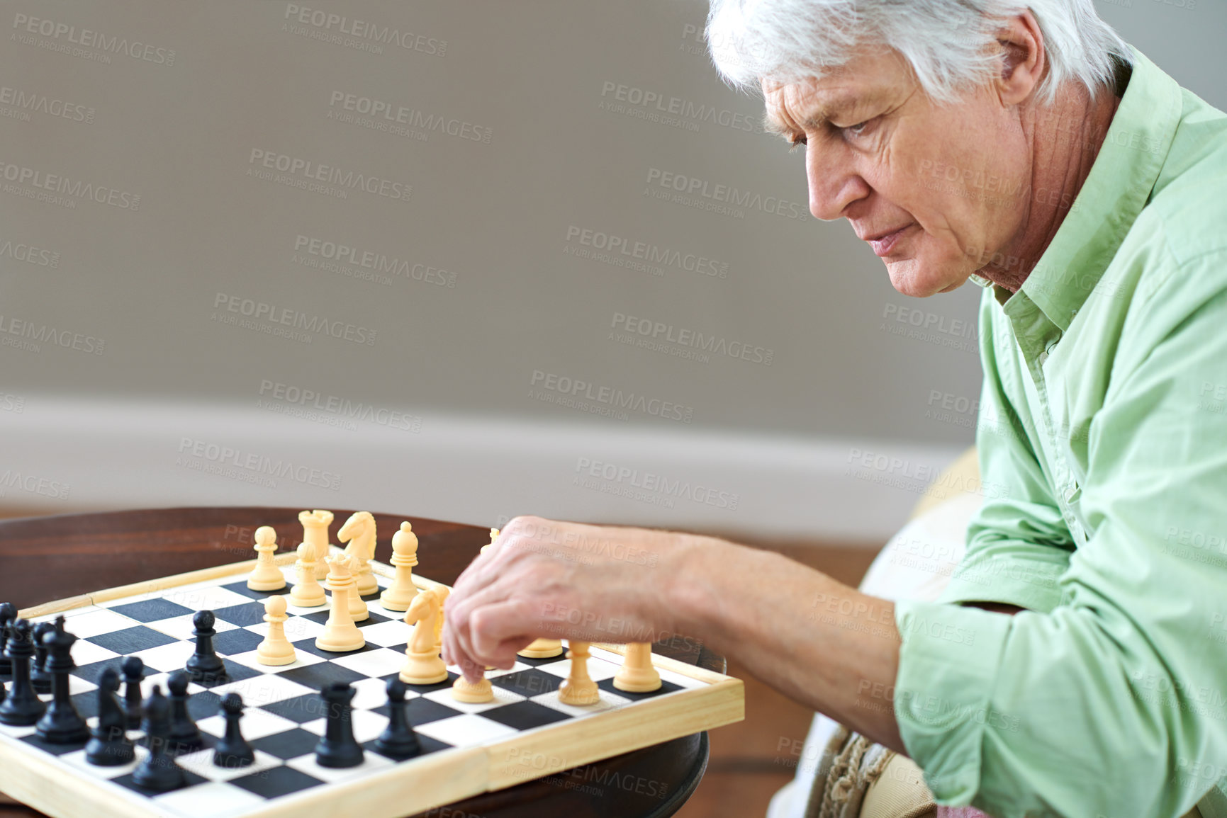 Buy stock photo Intelligent senior man playing a game of chess by himself. Elderly concentrated male looking serious and determined while playing a game of chess alone at home. Pensive male challenging himself