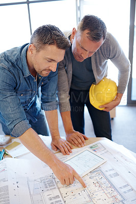 Buy stock photo Shot of two architects working together on a blueprint with the help of a digital tablet
