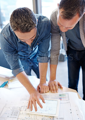 Buy stock photo Shot of two architects working together on a blueprint with the help of a digital tablet
