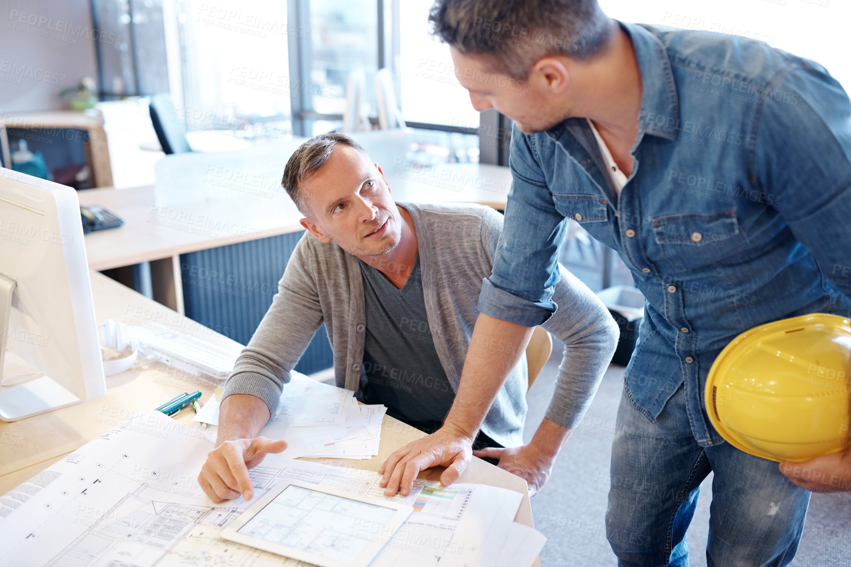 Buy stock photo Shot of two architects working together on a blueprint with the help of a digital tablet
