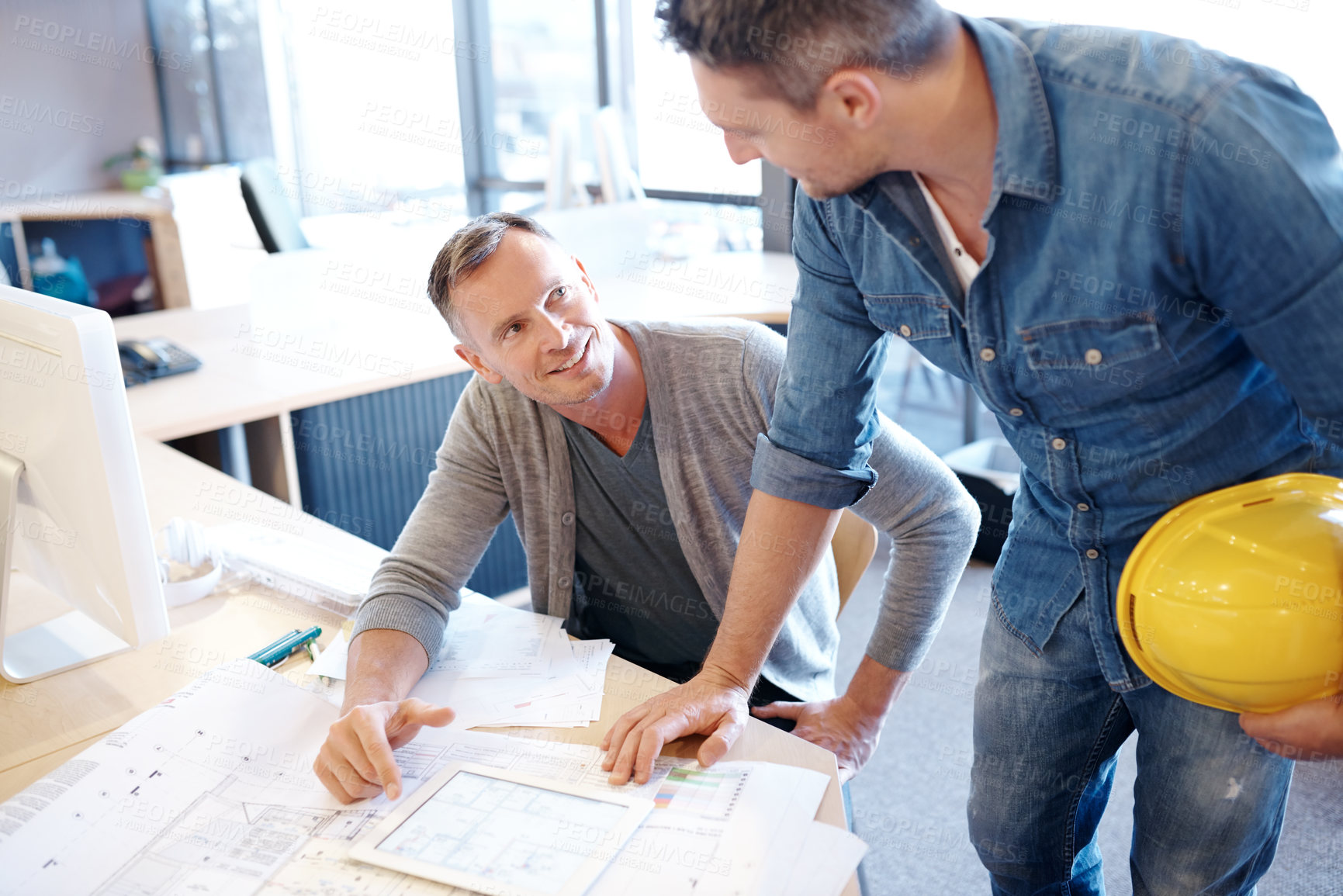 Buy stock photo Shot of two architects working together on a blueprint with the help of a digital tablet
