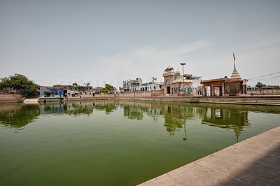 Buy stock photo Sacred pool, nature and water with tradition, spiritual and buildings in India, worship and travel. Empty, religion and outdoor with cleansing, Krishna and myth with culture, faith and tourism