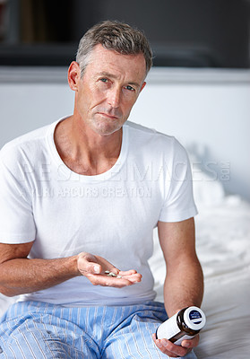 Buy stock photo Portrait of a serious mature man sitting on a bed with his medication