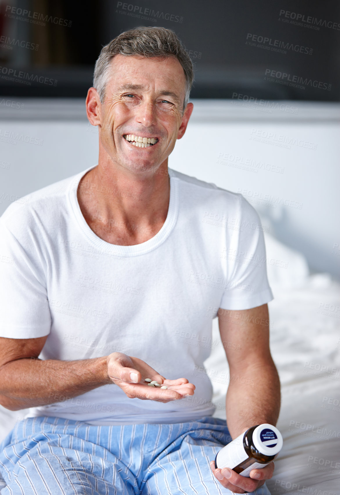 Buy stock photo Shot of a mature man sitting on a bed with his medication