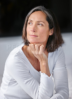Buy stock photo Shot of an attractive mature woman looking thoughtful while sitting on her bed 