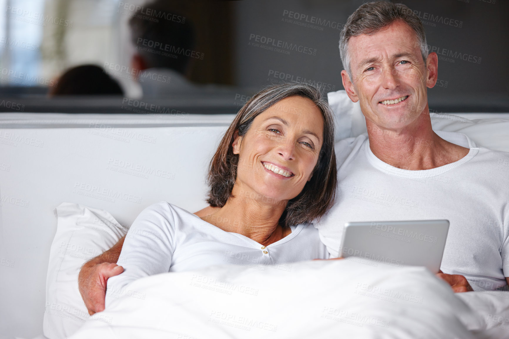 Buy stock photo Portrait of a happy mature couple sitting in bed with a digital tablet