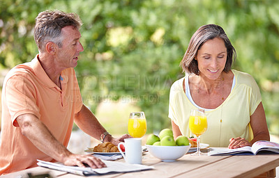 Buy stock photo Shot of a mature couple having breakfast together outdoors