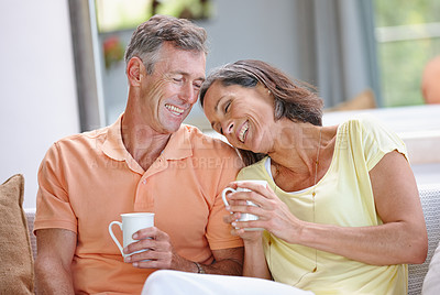 Buy stock photo Shot of a  loving mature couple having coffee while sitting on the sofa