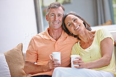 Buy stock photo Portrait of a  loving mature couple having coffee while sitting on the sofa