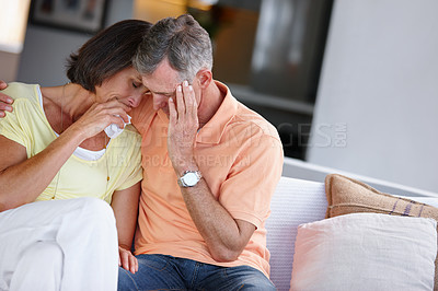Buy stock photo Shot of a mature married couple looking sad and distraught while sitting beside ach other