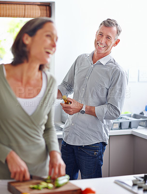 Buy stock photo Shot of a mature couple laughing while preparing a meal together in the kitchen