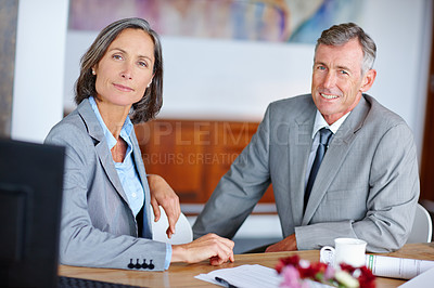 Buy stock photo Portrait of two mature business colleagues sitting beside each other at a desk