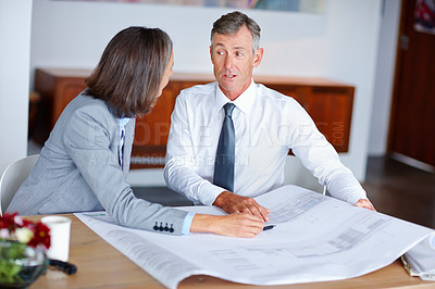 Buy stock photo Shot of two mature architects discussing blueprints in an office
