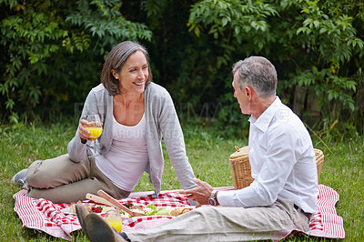 Buy stock photo Park, mature couple and picnic with food for nutrition, hungry and bonding together with communication. Happy people, man and woman with juice glass for drinking, beverage and commitment in marriage