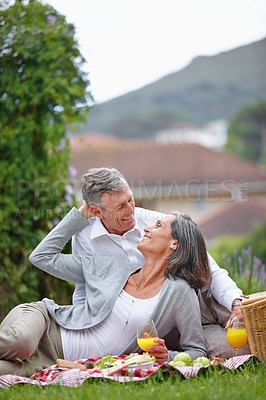 Buy stock photo Shot of a loving mature couple having a picnic on the grass