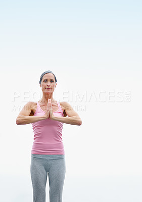 Buy stock photo Shot of an attractive mature woman doing yoga outdoors