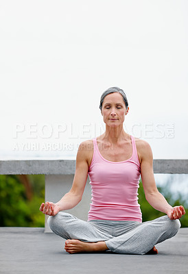 Buy stock photo Shot of an attractive mature woman practicing yoga in the lotus position