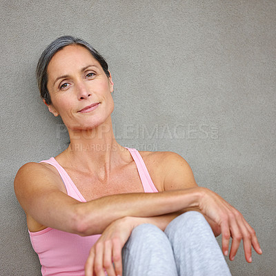 Buy stock photo Portrait of an attractive mature woman in gymwear sitting against a gray wall